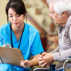 Nurse and patient in wheelchair discussing paperwork.