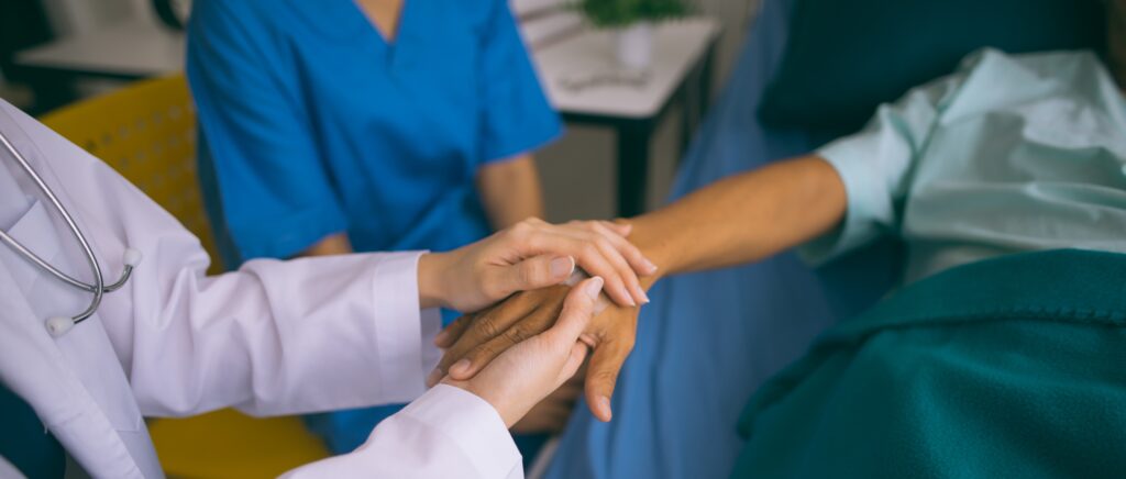 Doctor and clinician holding a hospitalized patient's hand.