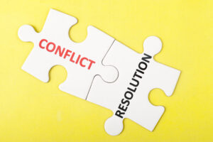 Two puzzle pieces with one with the word conflict on it and the other with the word resolution on it.