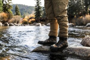 A stream with a fishing person standing on the rocks.