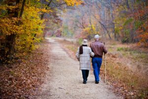 Older couple walking arm in arm on nature path.