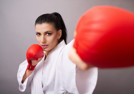 Woman in fighting stance with fighting gear on.