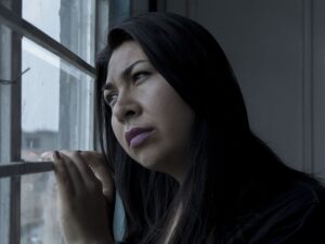Woman in pain looking out a window.