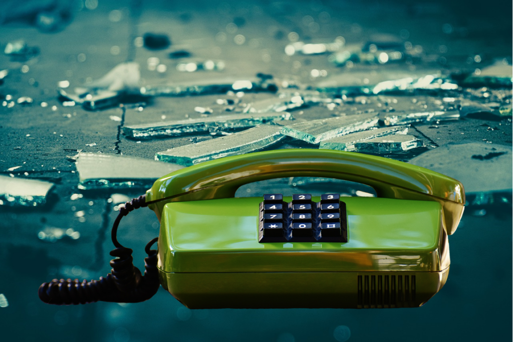 Telephone from the 1980's with broken glass behind.