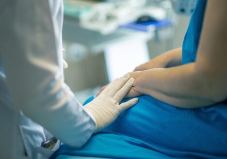 A caring doctor-patient moment. The doctor is setting their hand on the patient's hand.