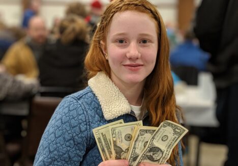 Teenage girl holding a donation at a fundraising event.