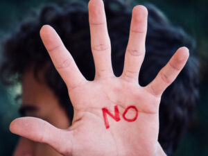 Person holding their had up with the word "no" inked on their palm.